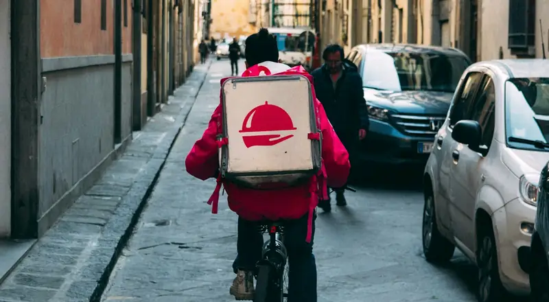 Entregador de bicicleta com mochila térmica na cidade