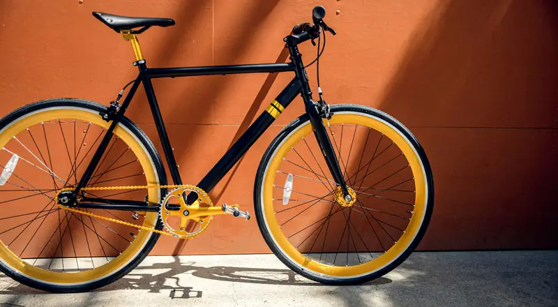 Bicicleta preta e amarela apoiada em parede